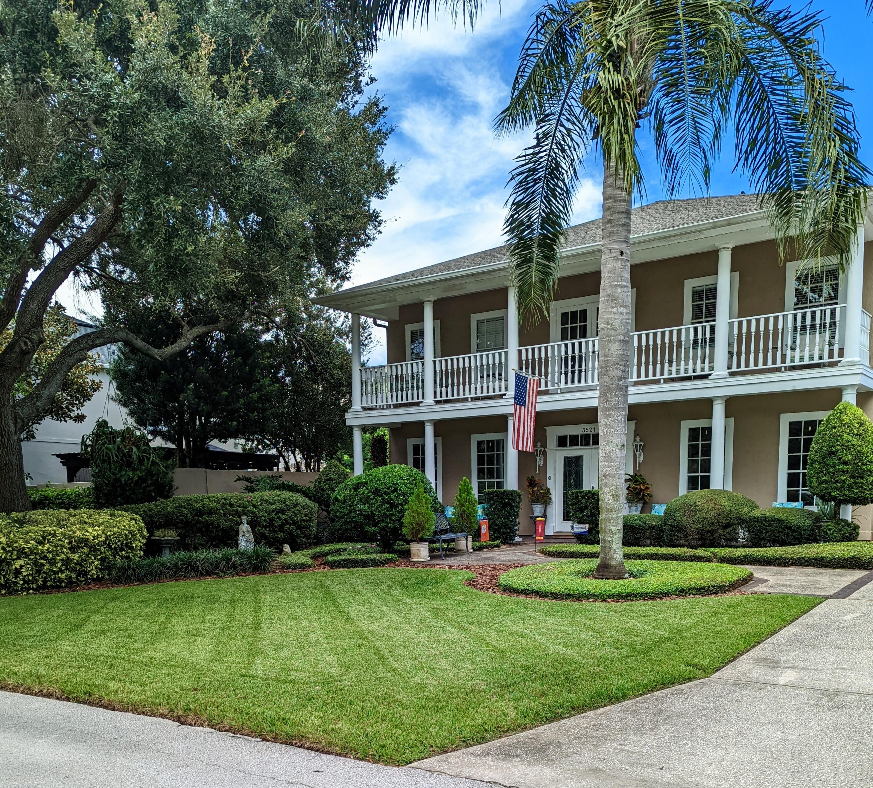 Elegant manicured lawn in Winter Park, Florida featuring tall palm tree, circular beds, and premium landscaping